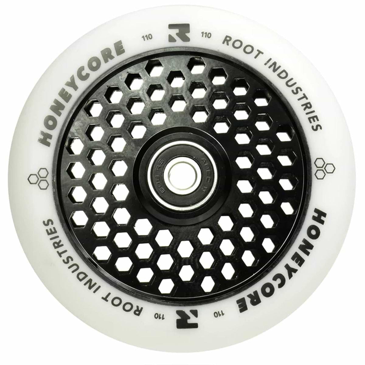 The Root Industries Honeycore 110mm Stunt Scooter Wheel in white and black boasts a distinctive honeycomb cut-out design on the core. It is equipped with premium Root bearings, and the brand's name is prominently displayed in bold along the outer edge for a sleek finish.