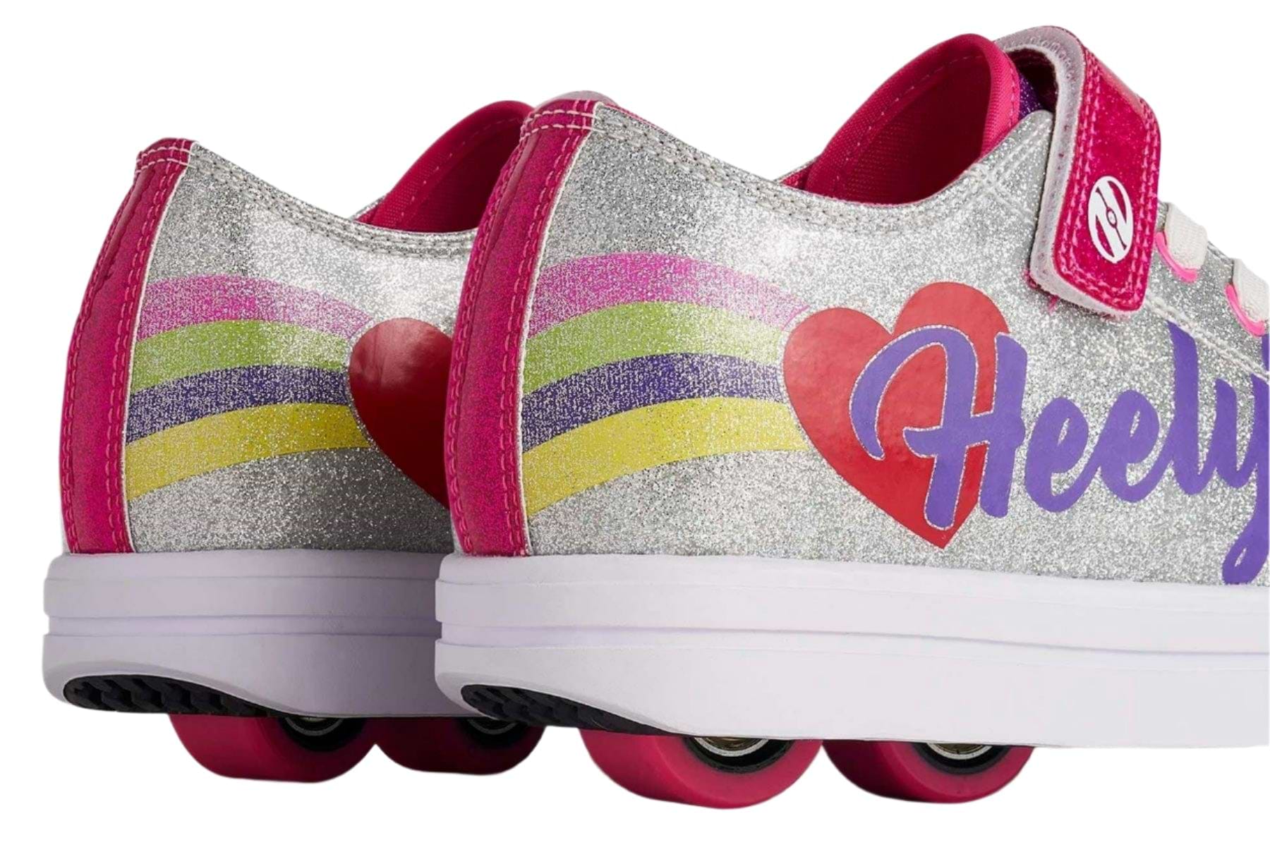Close-up of Heelys Snazzy X2 Girls Shoes in silver with rainbow stripes and heart details. Features two pink wheels per shoe, pink wheels on the heels, and "Heelys" in purple on the side. Brand: Heelys.