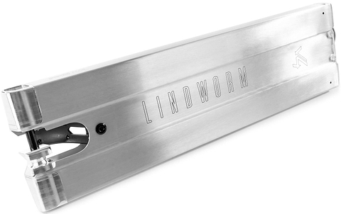 A raw Ethic DTC Lindworm V4 stunt scooter deck by Ethic, measuring 6.7″ x 22.8″ or 24.4″, features a brushed metal finish with sharp edges and an engraved logo, shown from an angle displaying the side and part of the rear wheel area.