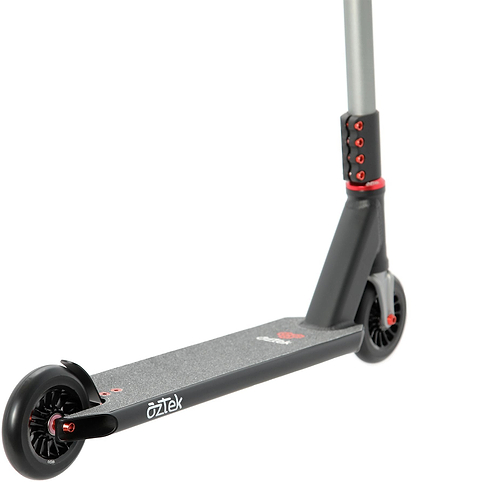 A close-up of the Aztek Corsa 2026 Complete Stunt Scooter - Satin Black shows its black and gray frame with striking red accents, featuring the deck, rear wheel, and part of the handlebar. This lightweight stunt scooter from Aztek includes grip tape on the deck and has “OZTEK” printed on the side, making it an excellent option for park scooter enthusiasts.