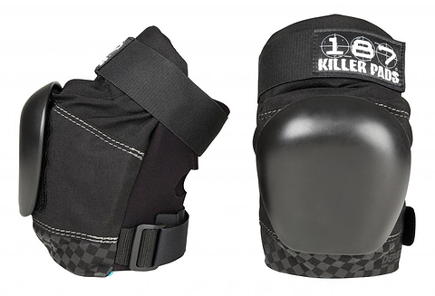 Two 187 Killer Pro Derby Knee Protection Pads in black are displayed, featuring adjustable straps and a rugged design suitable for action sports. The brand "187" is prominently visible on the upper section. One knee pad stands upright while the other lies on its side, highlighting the V-22™ Dual Density Foam cushioning for exceptional protection.
