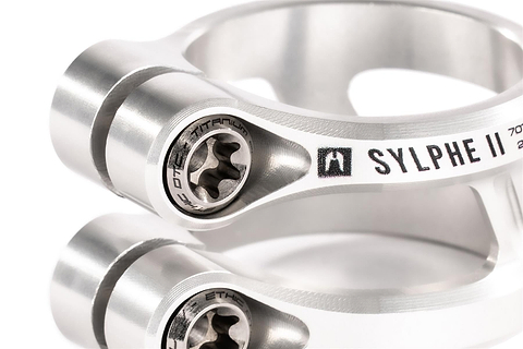 Close-up of two Ethic DTC Sylphe V2 2 Bolt Oversized Stunt Scooter Clamps in Raw, highlighting detailed bolts and smooth silver finish with engraved text—ideal lightweight clamp for stunt riders from Ethic.