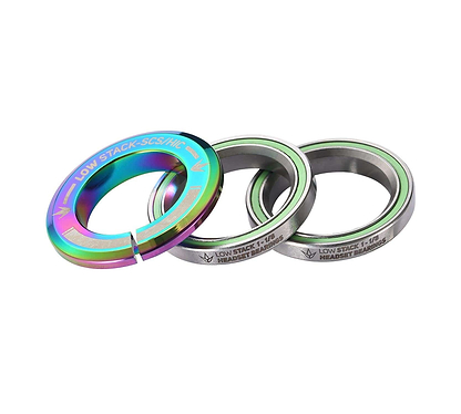 The Blunt Envy Low Stack SCS Integrated Stunt Scooter Headset features three metallic spacers with a stunning oil slick neochrome finish. The largest spacer is labeled for compatibility with the SCS compression system, while the others display measurement inscriptions. These circular spacers have a smooth outer texture.