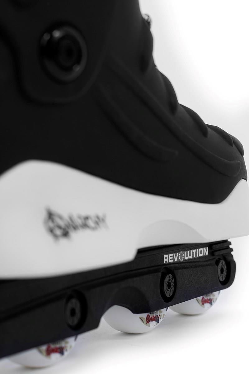 Close-up of Anarchy Revolution II Aggressive Inline Skates - Black, featuring a white sole and the "Anarchy" brand on the frame. These durable skates are designed for performance with a subtle logo near the heel and four wheels underneath, perfect for aggressive inline skating.