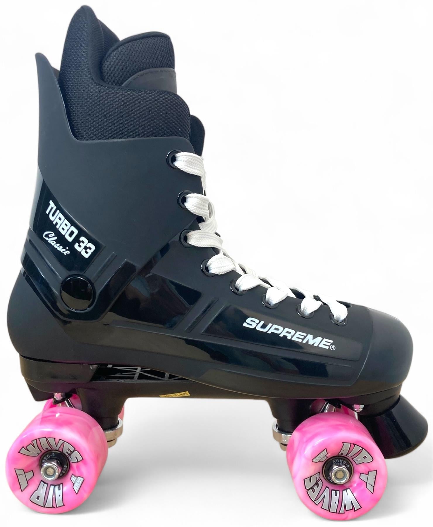 The Supreme Turbo 33 Nylon Quad Roller Skates - Black / Pink Swirl Wheels by Supreme features white laces and pink wheels labeled "WAVE" and "NMB," set against a plain white background. The skates are marked "TURBO 33 Classic.