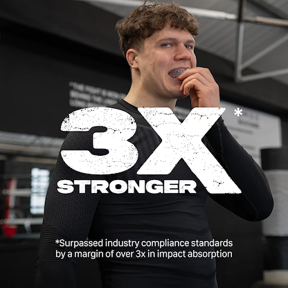 A young man in athletic wear bites into the Safejawz Intro Series Protection Mouthguard - Clear at the gym, showing its comfortable fit. Large text reads "3X STRONGER." Below: "Surpassed industry standards by 3x in impact absorption.
