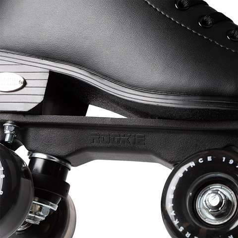 Close-up of the Rookie Classic 78 Quad Roller Skates - Black by Rookie, featuring part of the boot, metal plate, and two black wheels with white text. Laces and textured detailing showcase their classic style.