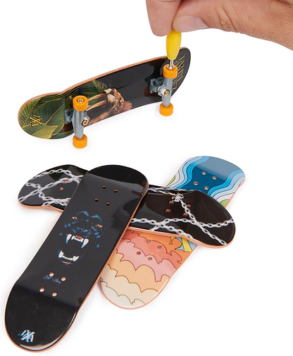 A hand uses a yellow tool to tighten wheels on a Tech Deck M01 Deluxe 4 Pack Fingerboard - Maxallure, with three other colorful Tech Deck boards featuring various designs displayed below.