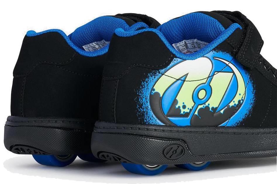 A close-up of the Heelys Kolect X2 Boys Shoes in Black/Royal/Green shows two wheels in the soles, blue interiors, and bold blue, green, and black graphics on the sides. Brand: Heelys.