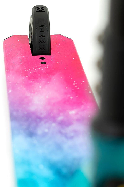 Close-up of the Slamm Mischief Complete Stunt Scooter - Nebula deck, showcasing its vibrant pink and blue design. The rear wheel is partially visible at the top, featuring 110mm wheels with a unique tire tread and Slamm brand lettering.