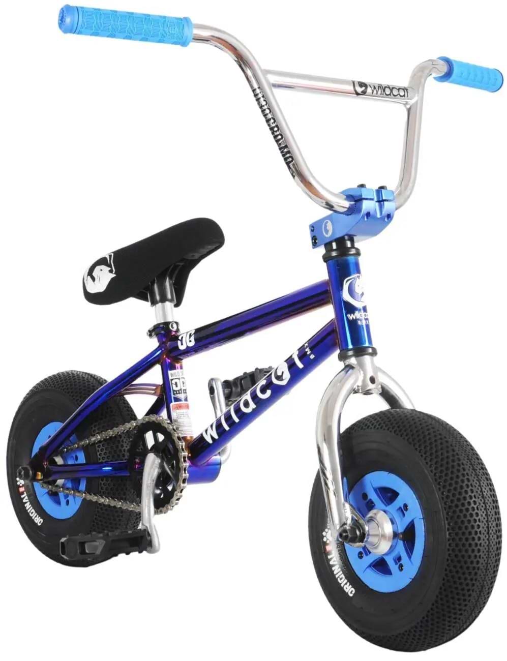 The Wildcat OG Original 3A Mini BMX Bike - Royal Blue by Wildcat features a compact metallic blue frame, PRO Street 65PSI tyres, light blue rims, 4130 chromoly steel handlebars with blue grips, and a black seat with a white graphic—perfect for trick riding.