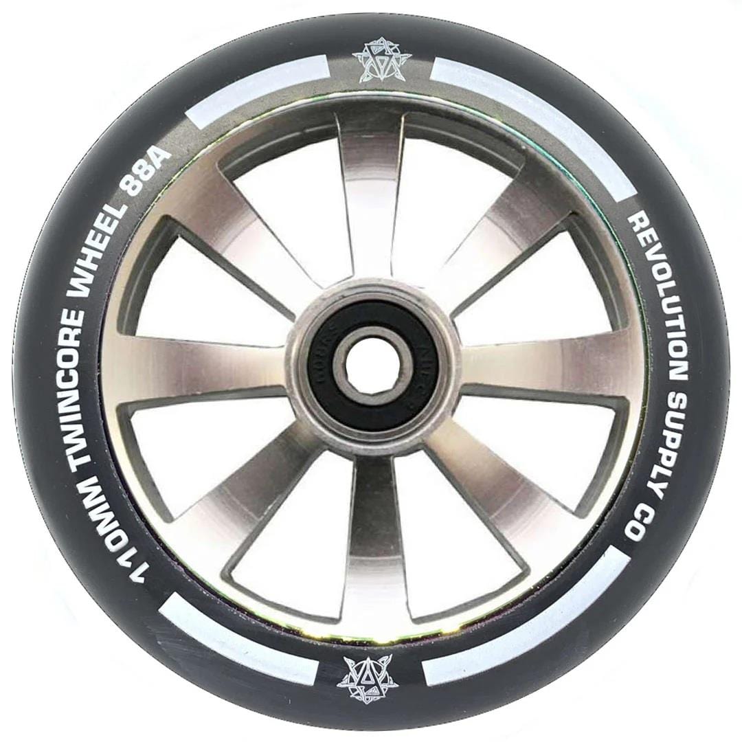 A close-up of the Revolution Twin Core 110mm Stunt Scooter Wheel - Raw shows its black and silver design, eight spokes, white "110MM TWINCORE WHEEL 88A" and "REVOLUTION SUPPLY CO." text, and a central ABEC 9 bearing for top performance.