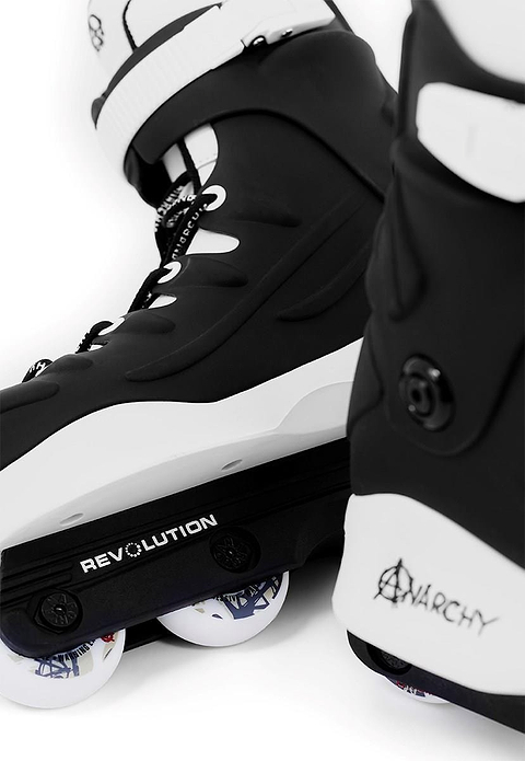 Close-up of two black Anarchy Revolution II aggressive inline skates, with bold "REVOLUTION" and "ANARCHY" branding. Ideal for beginner and intermediate skaters, the wheels have a subtle design with hints of color, enhancing tricks and grinds.