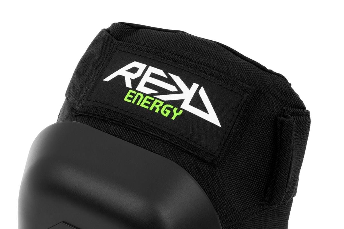 A close-up of the REKD Energy Patrol Ramp Knee Skate Protection Pads in black showcases a sleek design with a Velcro strap, prominently displaying the brand name "REKD ENERGY" in white and green. Crafted for high-impact activities, these pads are perfect for sports or protective use, offering exceptional knee protection.