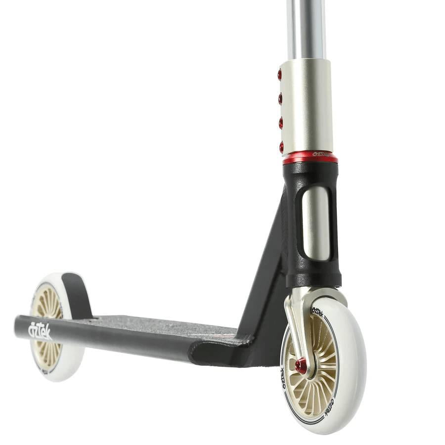 Close-up of the Aztek Corsa Complete Stunt Scooter in black by Aztek, featuring silver details, white wheels, red accents, and focusing on the deck, fork, and front wheel against a white background.