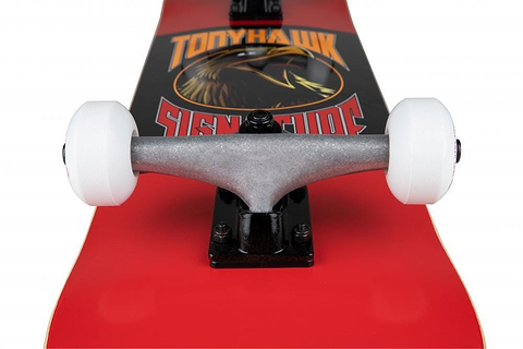 Close-up of the Tony Hawk SS 180+ Bird Logo Red Complete Skateboard (8" x 31.5") with silver trucks and white wheels, featuring the bold Tony Hawk graphic—ideal for beginners.