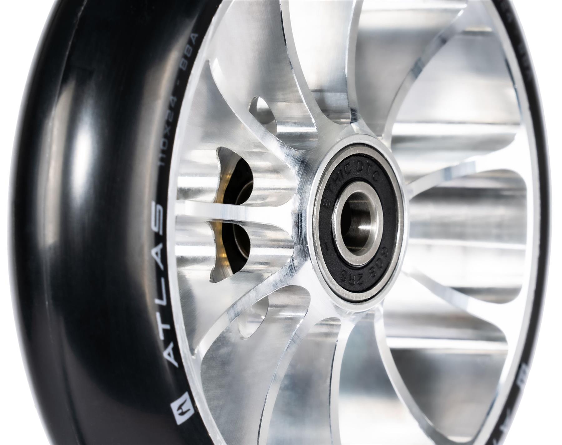 Close-up of the Ethic DTC Atlas 110mm Stunt Scooter Wheel in Raw, featuring a shiny lightweight design, black rubber tire with "ATLAS" in white on the sidewall, and a visible center ball bearing.