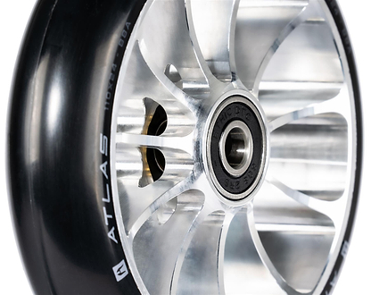 Close-up of the Ethic DTC Atlas 110mm Stunt Scooter Wheel in Raw, featuring a shiny lightweight design, black rubber tire with "ATLAS" in white on the sidewall, and a visible center ball bearing.