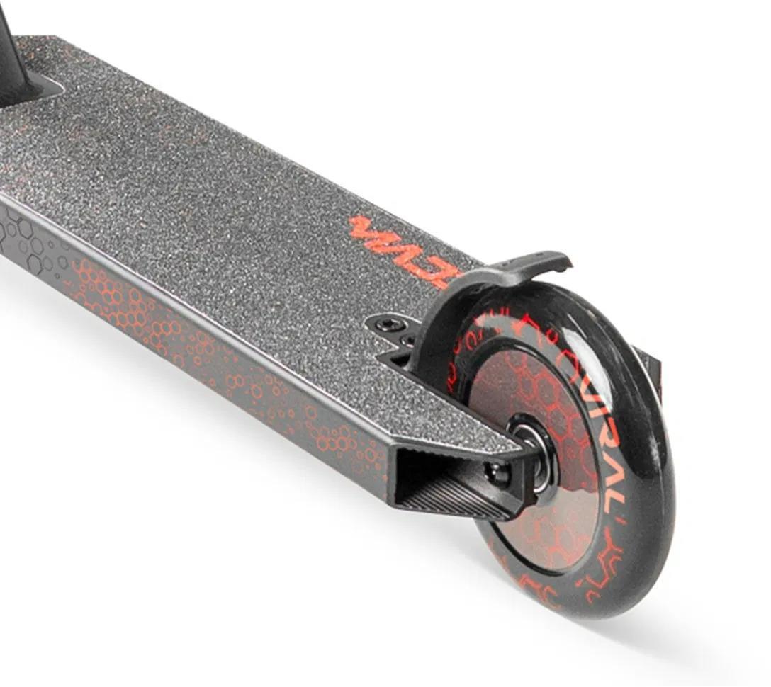 Close-up of the rear wheel and deck on the Madd Gear Viral Rave Complete Stunt Scooter - Inferno by MGP, featuring red hexagonal designs and text on the wheel, a textured grip deck surface, and a rear fender brake.