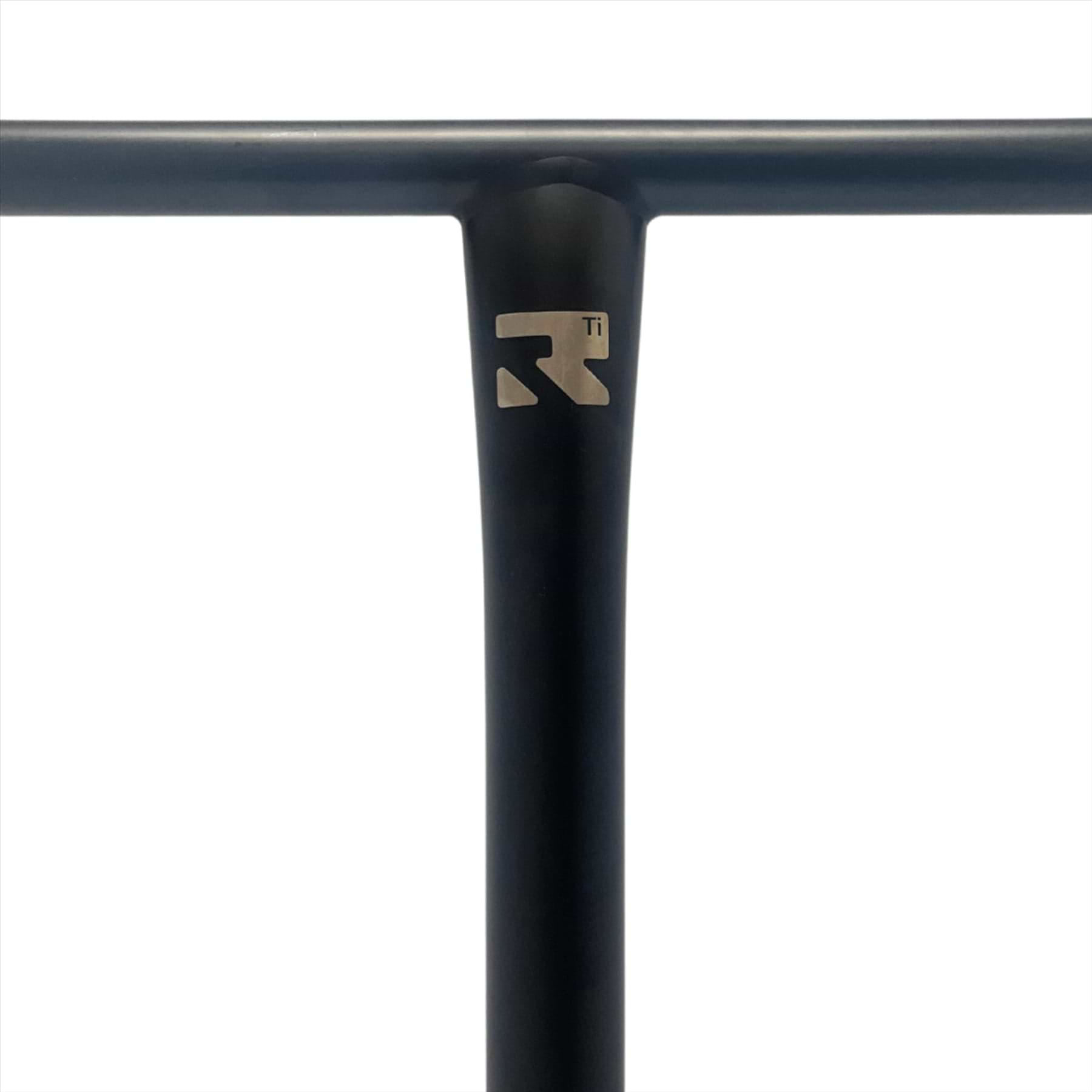 Close-up of a black T-shaped scooter handlebar with a metallic logo near the joint. The Root Industries AIR Titanium Oversized HIC Stunt Scooter T-Bars in Black (690mm x 600mm) feature a sleek and minimalist design, showcasing one of the strongest titanium constructions available, set against a plain white background for emphasis.