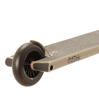 Close-up view of the rear wheel and deck of an Aztek Siren Complete Street Stunt Scooter in Zircon Sand, featuring a textured footboard, black spoked wheel, and the Aztek logo on its metallic frame.