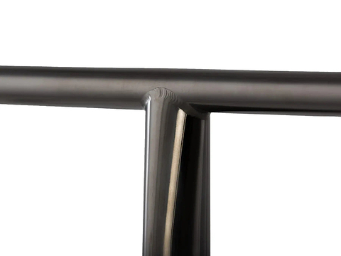 The close-up showcases the Lucky Obsidian Titanium Oversized SCS Stunt Scooter T-Bar in black, featuring a sleek metal joint with a T-shaped intersection. The smooth, shiny surface reflects light, emphasizing the precise connection of cylindrical rods, reminiscent of the artistry seen in Lucky's Titanium Scooter Bars.