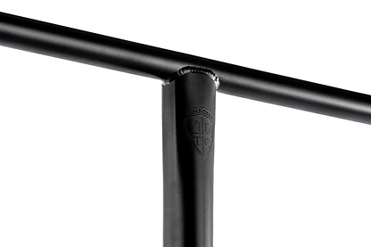 Close-up of the Ethic DTC Tenacity V2 steel oversized HIC stunt scooter T-bars in black, featuring a welded joint. The joint displays an embossed logo resembling a shield with letters inside. The white background highlights the lightweight design and craftsmanship, showcasing its high-quality steel construction by Ethic.