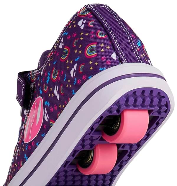 A close-up shows Heelys Snazzy X2 Girls Shoes in purple with multicolored rainbow designs and pink wheels, featuring ABEC 3 bearings, set against a plain background.