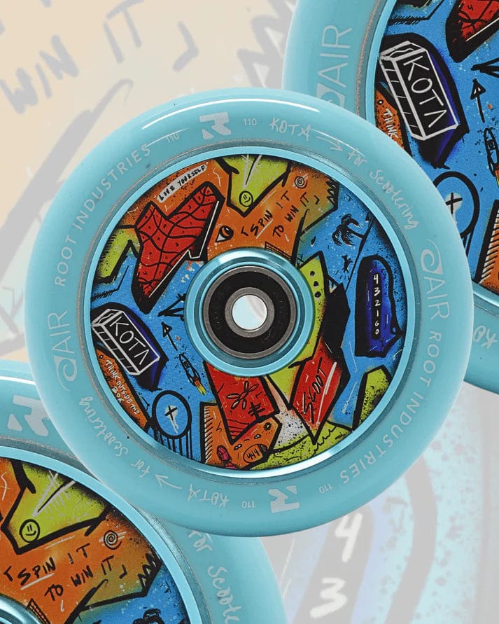 A close-up of the Root Industries x KOTA Limited Edition AIR 110mm Stunt Scooter Wheel in blue, featuring vibrant abstract graffiti art on the hub and "ROOT INDUSTRIES AIR" with "110 mm" text on the rim.