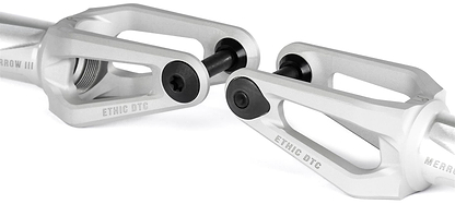 Close-up of two Ethic DTC Merrow V3 8/12STD HIC Stunt Scooter Forks in Raw by Ethic, featuring black bolts and angular design, engraved "ETHIC DTC," displayed against a white background.