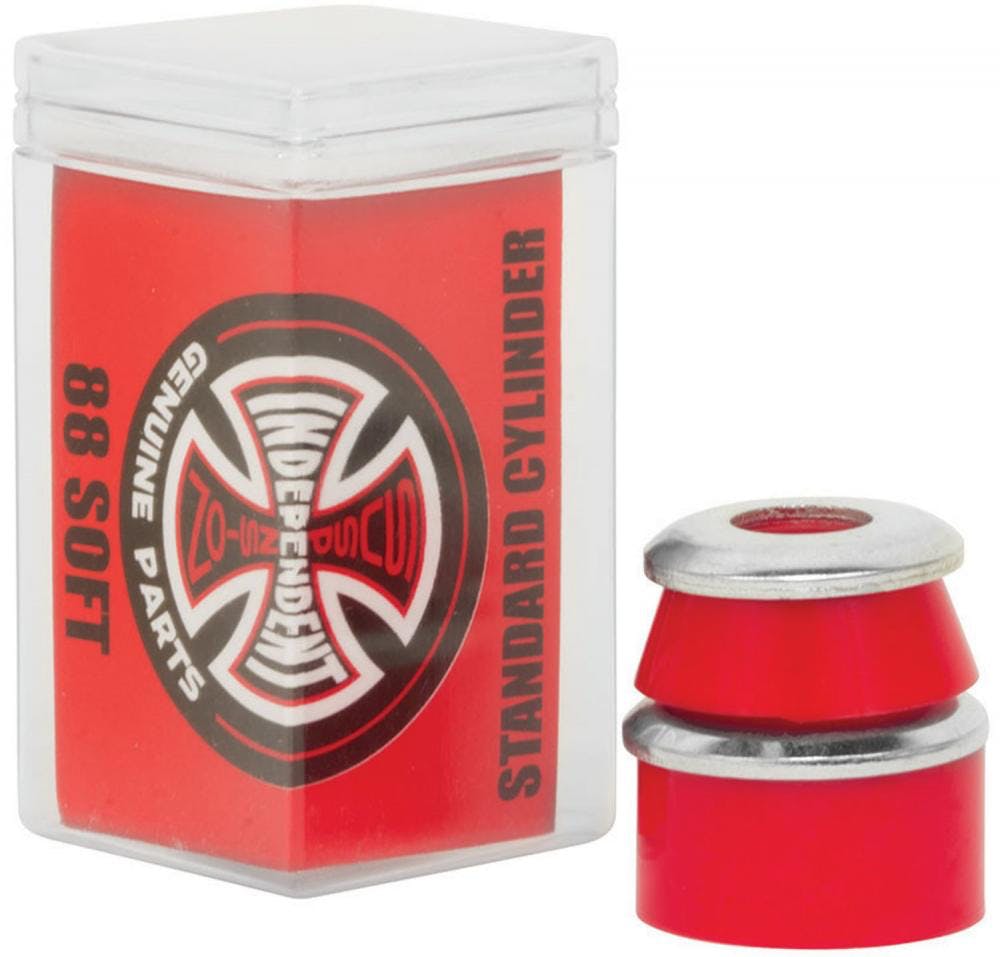 A transparent plastic container labeled "Independent Standard Cylinder Red Skateboard Bushings - 88A" contains urethane formula red skateboard bushings. Next to the box is a pair of cylindrical bushings accompanied by silver-colored washers, completing the set from Independent.