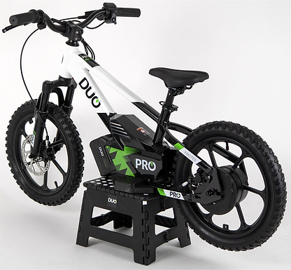 The Duo 16" Master Pro Kids Electric Balance Bike in white and black is shown on a black stand against a white background. This sturdy bike features thick tires, bold “DUO” branding, and is designed for kids.