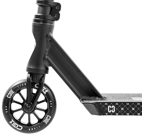 Close-up of the CORE CG1 Complete Stunt Scooter - Black by CORE, highlighting the textured diamond-patterned deck, sturdy fork, and wheel featuring "CORE" in white letters.