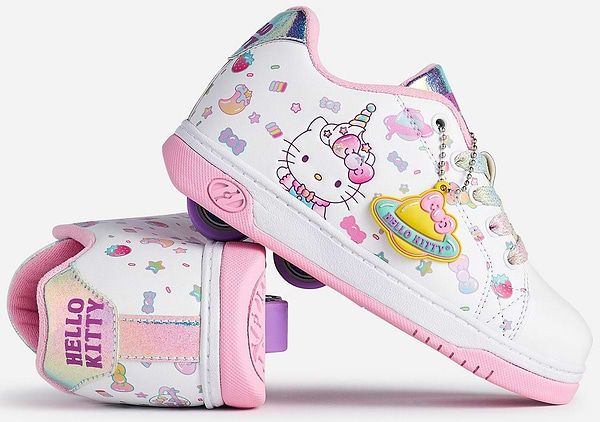 Two Heelys x Hello Kitty Split X2 Girls Heelys in white and pink, featuring unicorn, rainbow, star, and heart designs. One shoe is upright; the other is on its side, displaying "HELLO KITTY" text and a colorful planet charm. Brand: Heelys.