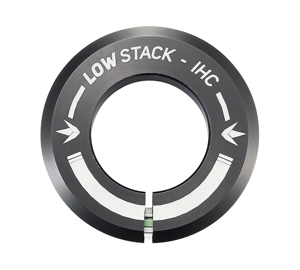 The Blunt Envy Low Stack IHC Integrated Stunt Scooter Headset - Black features a black circular metal ring with a split at the bottom, part of the IHC compression system. It is engraved with "LOW STACK - IHC" alongside two inward-pointing arrows, ensuring compatibility with sealed bearings for a smooth ride.