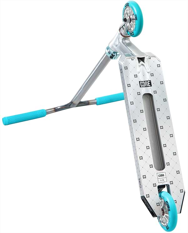 The CORE CG1 Complete Stunt Scooter in Raw/Teal is shown at an angle, featuring blue handle grips and wheels. The patterned deck displays the "CORE" branding, with the scooter tilted to highlight its underside and wheels.