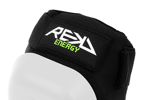 Close-up of the REKD Energy Patrol Ramp Knee Skate Protection Pads in white, featuring a black protective design with the brand's distinctive logo in white and green. This gear is designed for extreme sports, showcasing a smooth, slightly curved surface and an adjustable Velcro strap to ensure optimal knee protection against impact energy.