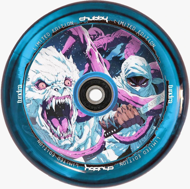 The Chubby Hollowcore 110mm Stunt Scooter Wheel - Arctic by Chubby showcases a blue design with artwork of a fierce white yeti baring sharp teeth and a hooded figure holding a knife, all set against a snowy night sky. The rim is marked with “Limited Edition” and “Lunar.”.