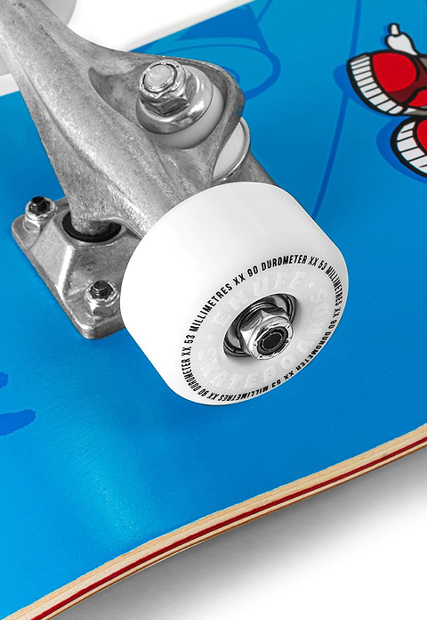 Close-up of an Enuff Skully Blue Complete Skateboard - 7.75″ x 31.5″, featuring a blue deck with a cartoon skull graphic, a silver truck, and a white wheel.