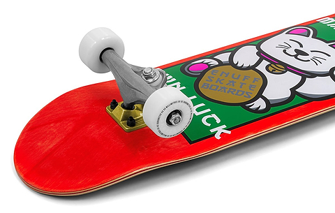 A close-up of the Enuff Lucky Cat Red Complete Skateboard (8.0" x 32") shows a white lucky cat graphic and "ENUFF SKATE BOARDS" text. Silver trucks and white wheels make it ideal for beginners in street or park skating.