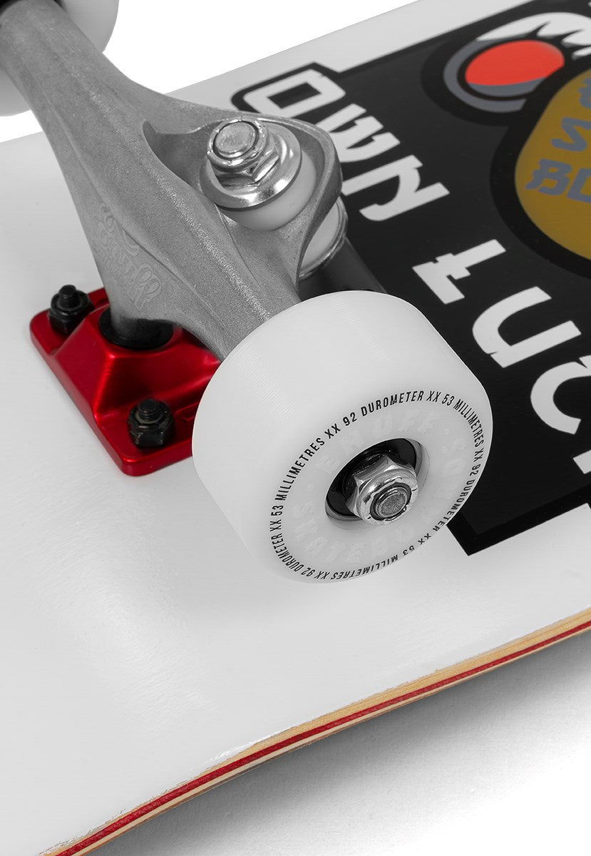 Close-up of a skateboard wheel and truck attached to a white Enuff deck featuring a black and red sticker. The wheel displays text, while the truck has a red baseplate. The Enuff Lucky Cat White Complete Skateboard - 8″ x 32″ is ideal for street and park skating, making it an excellent choice for beginner skateboard enthusiasts.
