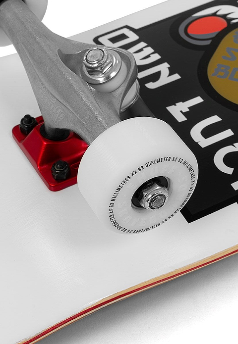 Close-up of a skateboard wheel and truck attached to a white Enuff deck featuring a black and red sticker. The wheel displays text, while the truck has a red baseplate. The Enuff Lucky Cat White Complete Skateboard - 8″ x 32″ is ideal for street and park skating, making it an excellent choice for beginner skateboard enthusiasts.