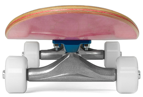 Close-up ground-level shot of the Enuff Lucky Cat Mini Pink Complete Skateboard – 7.25″ x 29.5″, featuring white wheels, silver trucks with a blue baseplate, and a wooden deck with a vibrant pink underside. Ideal as a beginner skateboard or kids skateboard from Enuff.