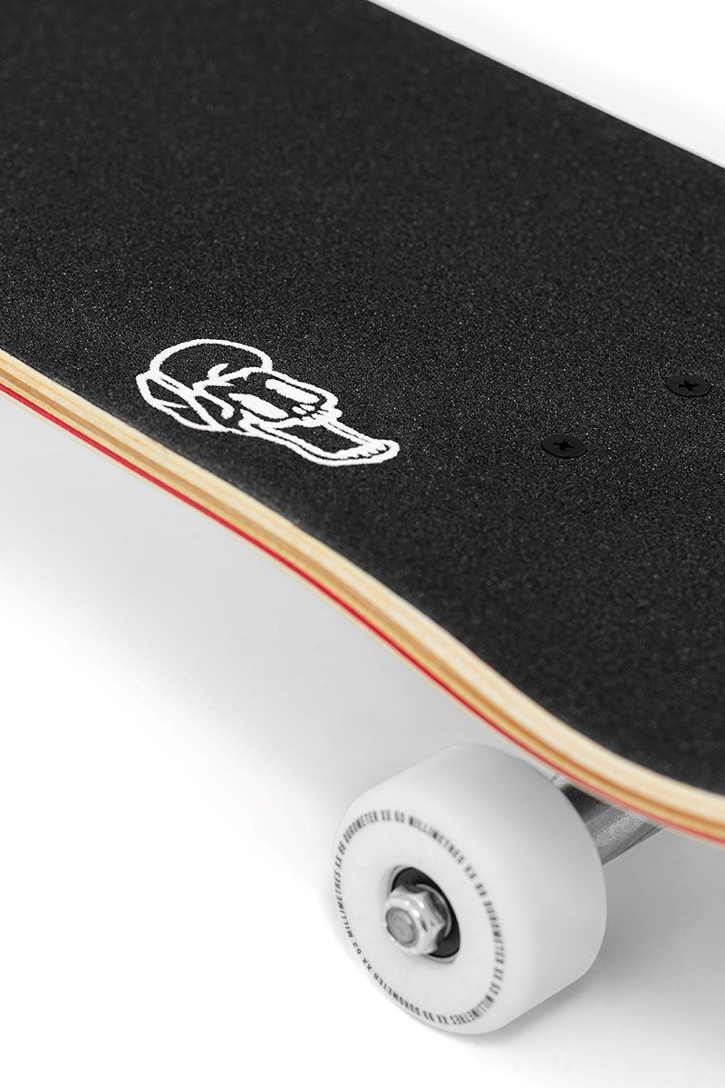 Close-up of the Enuff Three Tier Reloaded Natural Complete Skateboard (8.0" x 32.0") by Enuff, showing its 7-ply maple deck with black grip tape, white skull graphic, visible wood edge, one white wheel, and ABEC 7 bearings.