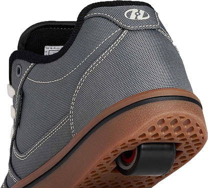 Close-up of the back of a gray sneaker with white stitching and a brown sole, featuring a retractable wheel in the heel—perfectly showcasing the Heelys Pro 25 Boys Shoes in Grey / Antique White / Black by Heelys.
