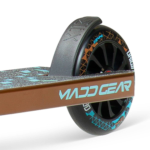 Close-up of the rear wheel on the lightweight Madd Gear (MGP) VX Origin IV 500 Complete Stunt Scooter - Deltoid, showing "MADD GEAR" on the brown deck and a patterned black wheel.