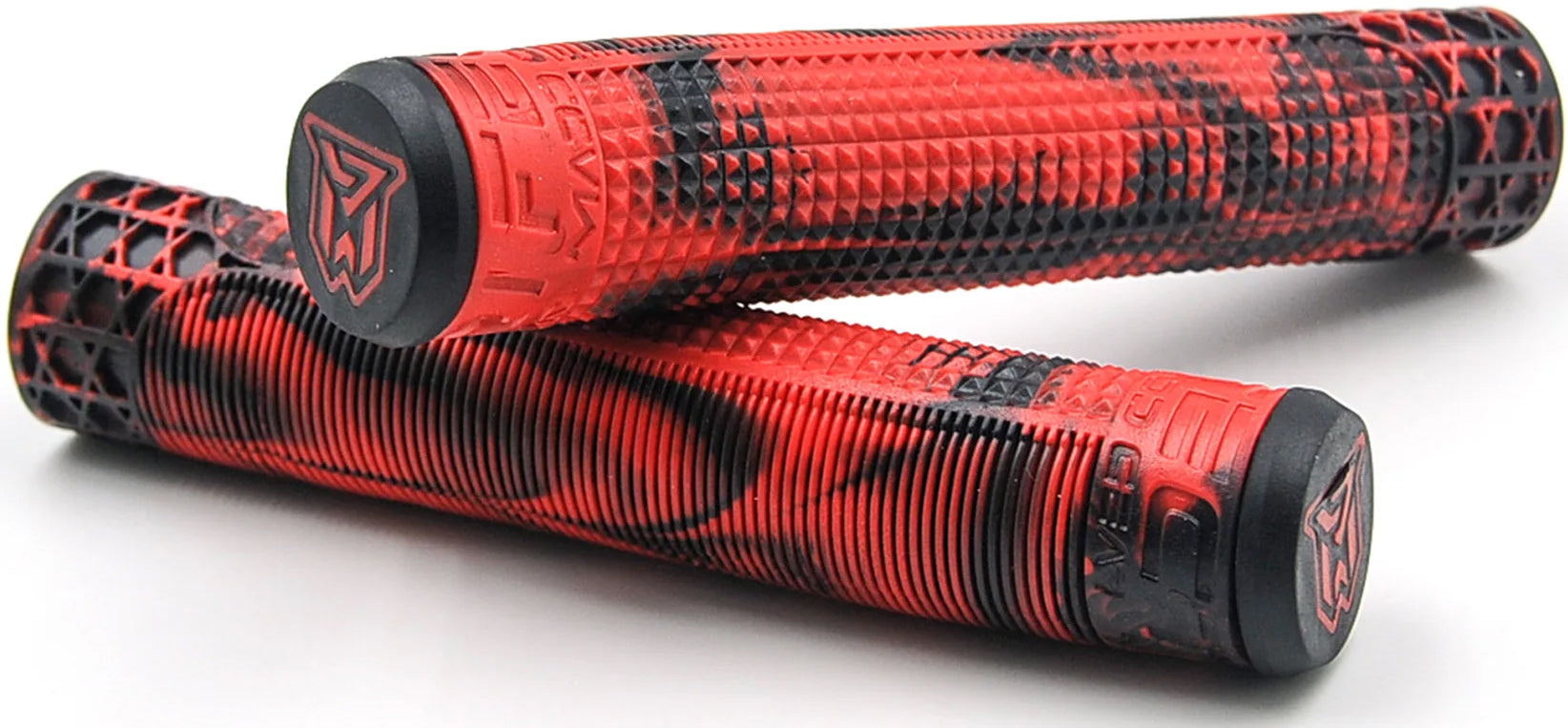 A pair of Madd Gear (MGP) MGP Trifecta Red / Black Stunt Scooter Grips (150mm), featuring bold red and black geometric texturing, are stacked on a white surface. Each grip is equipped with a black end cap displaying the stylized Madd Gear logo, making them versatile accessories—perfect as replacement grips or an upgrade for your stunt scooter.