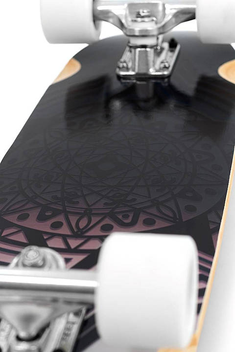 Close-up of the Mindless Drifter Cruiser Skateboard 28″ x 8″ - Black, featuring white wheels and trucks, with a black deck adorned in purple and pink geometric and circular patterns.