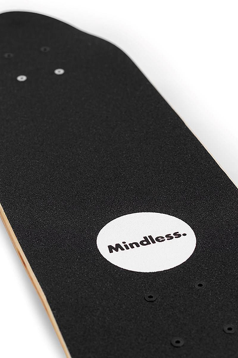 Close-up of the Mindless Drifter Cruiser Skateboard 28″ x 8″ - Black, featuring a white circle and “Mindless.” on the grip tape. Four empty hardware holes are visible.