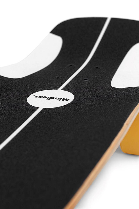 Close-up of the Mindless Soul Surf Skate Cruiser Skateboard 29.5″ x 9.75″ - Brown, featuring black grip tape with white markings and “mindless” in the center, resting on a yellow block.
